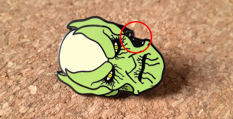 A pin with an area missing coloured enamel
